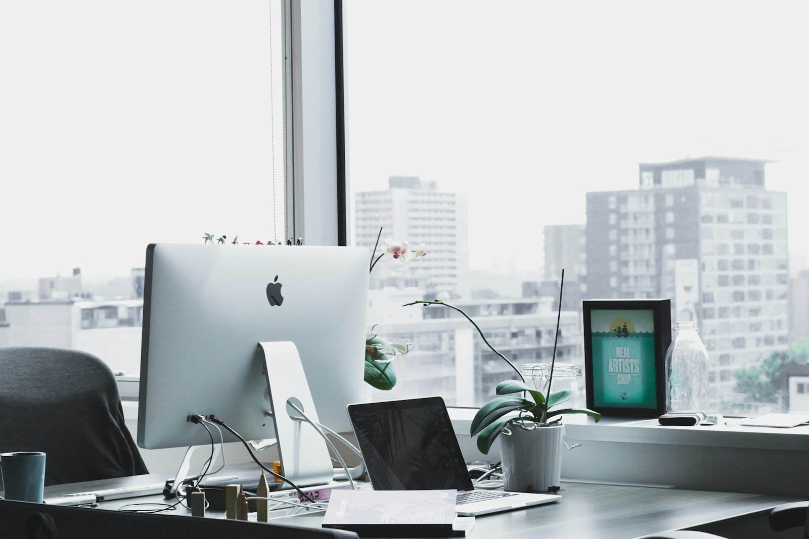 Bright office with a computer in front of a large window overlooking the city